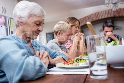 Multi-generation family praying before having meal