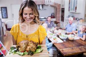 Happy woman holding a tray of roasted turkey