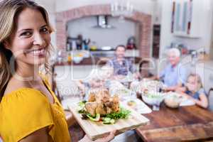 Portrait of happy woman holding a tray of roasted turkey