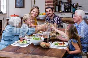 Multi-generation family toasting glass of wine while having meal