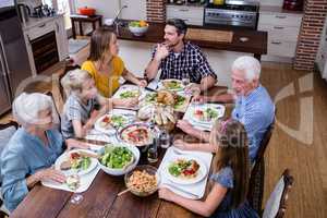 Multi-generation family talking while having meal in kitchen