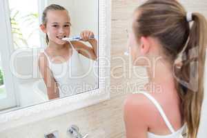 Happy girl brushing her teeth in bathroom