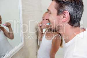Father and daughter brushing their teeth in the bathroom