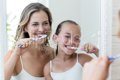 Mother and daughter brushing their teeth in the bathroom