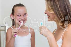 Mother and daughter brushing their teeth in the bathroom