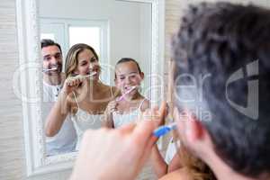 Parents and daughter brushing their teeth in the bathroo