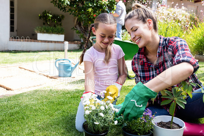 Smiling mother and daughter gardening together in garden