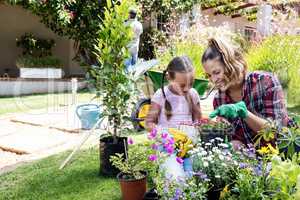 Smiling mother and daughter gardening together in garden
