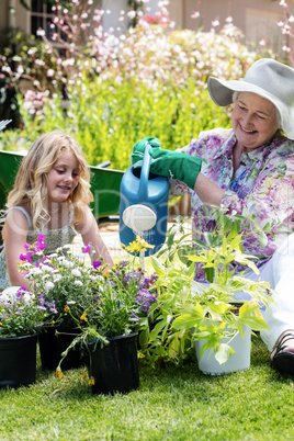 Grandmother and granddaughter watering the plants in the garden