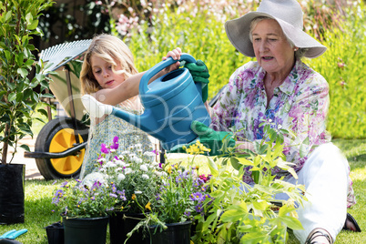 Grandmother and granddaughter watering the plants in the garden