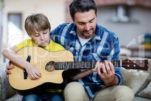 Father and son playing a guitar