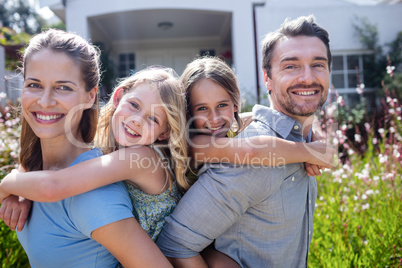 Portrait of parents giving a piggy back to daughters