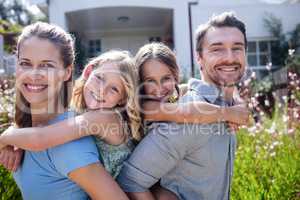 Portrait of parents giving a piggy back to daughters