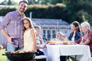 Father and daughter at barbecue grill while family having lunch