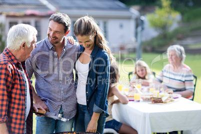 Couple and a senior man at barbecue grill preparing a barbecue