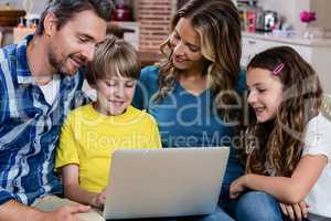 Parents and kids sitting on sofa and using a laptop