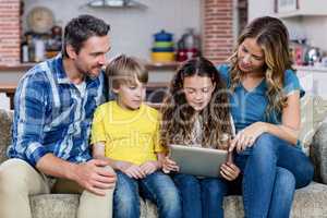 Parents and kids sitting on sofa and using a digital tablet