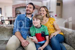 Parents and son watching television in living room
