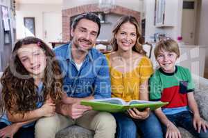 Portrait of happy family sitting on sofa with photo album