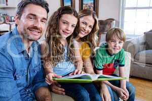 Portrait of happy family sitting on sofa with photo album