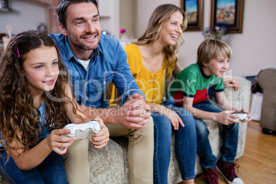 Family sitting on sofa and playing video game