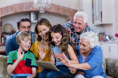 Multi-generation family waving hands while using digital tablet