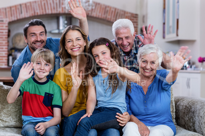 Portrait of multi-generation family sitting on sofa and waving h