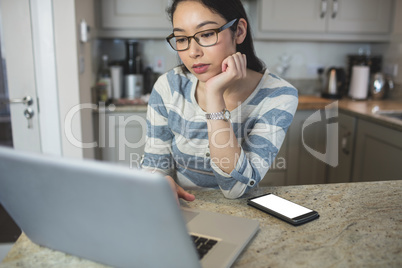 Young woman using a laptop in the kitchen