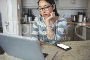 Young woman using a laptop in the kitchen