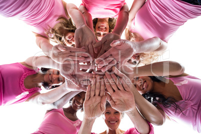 Women in pink outfits joining in a circle for breast cancer awar