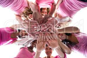 Women in pink outfits joining in a circle for breast cancer awar
