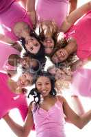 Women in pink outfits standing in a huddle for breast cancer awa