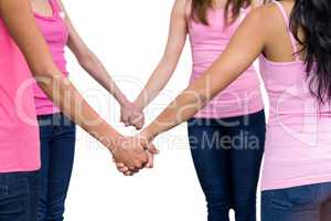 Women in pink outfits joining in a circle for breast cancer awar