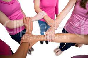 Women in pink outfits joining in a circle for breast cancer awar