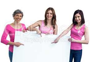Women in pink outfits holding board for breast cancer awareness