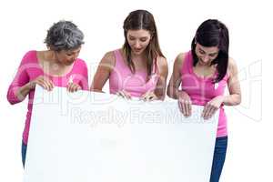 Women in pink outfits holding board for breast cancer awareness