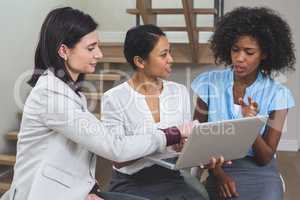 Female business colleagues discussing on laptop