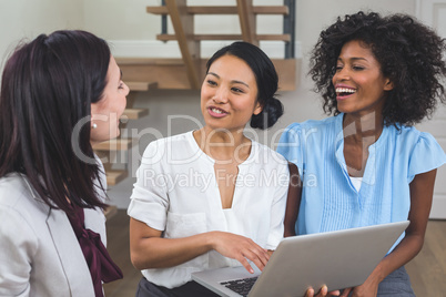 Female business colleagues discussing on laptop