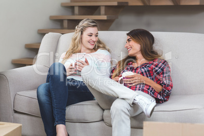 Two beautiful women holding a cup of coffee and talking in the l