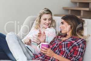 Two beautiful women holding a cup of coffee and talking in the l