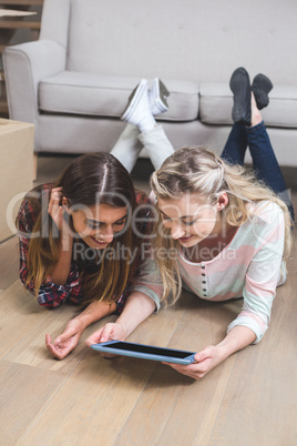 Friends lying together on the floor and using digital tablet