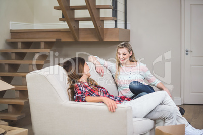 Two beautiful women talking with each other while relaxing on so