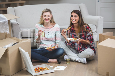 Two beautiful woman having pizza in the new house