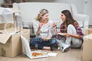 Two beautiful woman having pizza in the new house