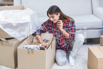 Beautiful woman unpacking carton boxes