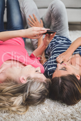 Two beautiful women lying on rug and looking at the mobile phone