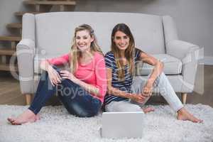 Two beautiful women sitting with a laptop in living room