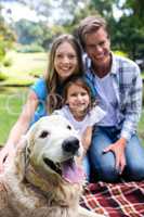 Happy family sitting in the park with their dog