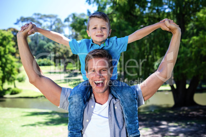 Happy father carrying his son on the shoulder in the park