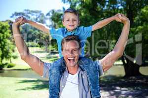 Happy father carrying his son on the shoulder in the park